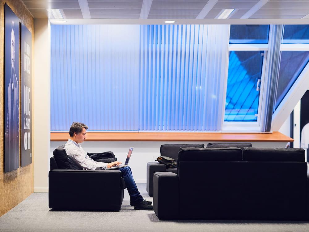 Man in zetel met laptop in grote ruimte