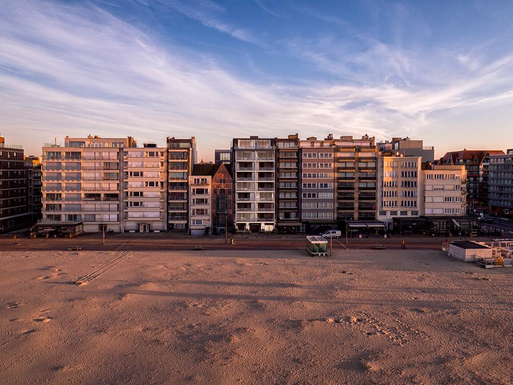 Strand met op achtergrond appartementsgebouwen en zeedijk